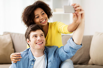 Image showing happy couple with smartphone taking selfie at home