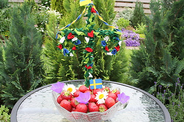 Image showing Swedish strawberries for Midsummer with may-pole in background