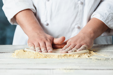 Image showing Closeup hand of chef baker in white uniform making pizza at kitchen