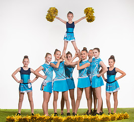 Image showing The group of teen cheerleaders posing at white studio