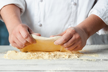 Image showing Closeup hand of chef baker in white uniform making pizza at kitchen