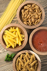 Image showing Variety of Pasta Wooden Bowls Cutting Boards Marinara Sauce