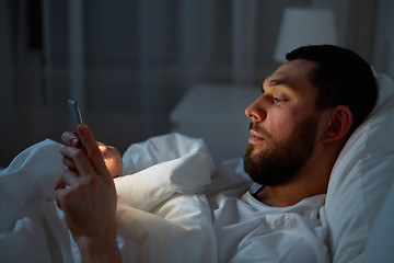 Image showing man with smartphone in bed at night