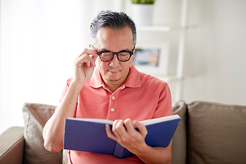 Image showing man in glasses reading book at home