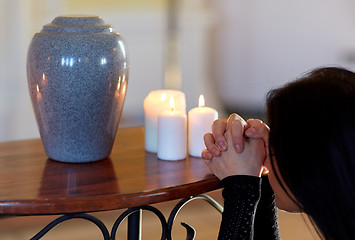 Image showing sad woman with funerary urn praying at church