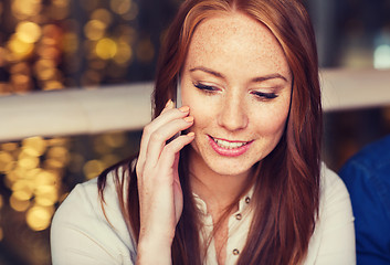 Image showing happy woman calling on smartphone at restaurant