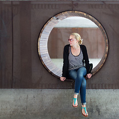 Image showing Young thoughtful woman relaxing on bench in city park.