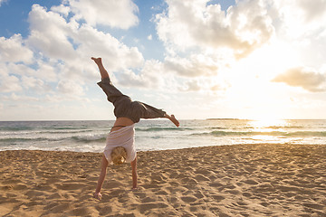 Image showing Free Happy Woman Turning Cartwheel Enjoying Sunset on Sandy Beach.