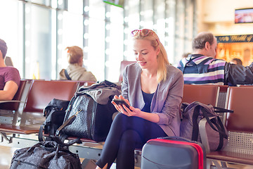 Image showing Female traveler using cell phone while waiting on airport.