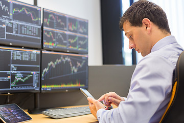 Image showing Stock broker trading online with mobile phone application.