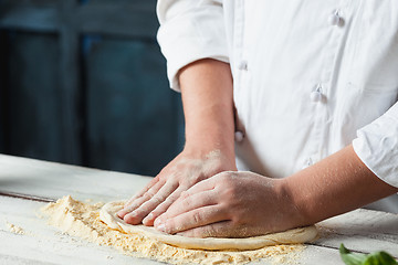 Image showing Closeup hand of chef baker in white uniform making pizza at kitchen