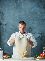 Image showing Closeup hand of chef baker in white uniform making pizza at kitchen