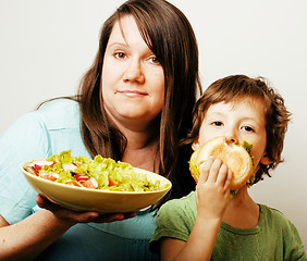 Image showing mature woman holding salad and little cute boy with hamburger te