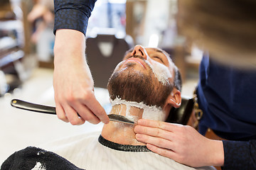 Image showing man and barber with straight razor shaving beard