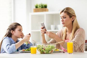 Image showing sad girl looking at her mother with smartphone