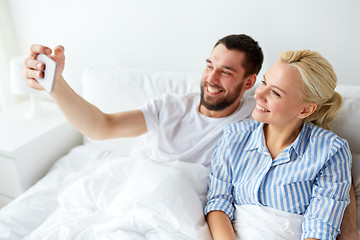 Image showing happy couple with smartphone taking selfie at home