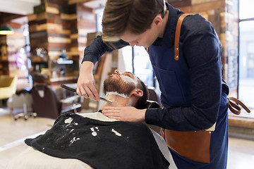 Image showing barber with straight razor shaving clients beard