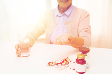Image showing happy senior woman with water and pills at home