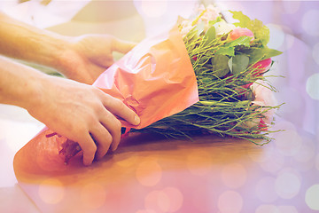 Image showing florist wrapping flowers in paper at flower shop