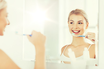 Image showing woman with toothbrush cleaning teeth at bathroom