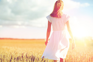 Image showing young woman in white dress walking along on field