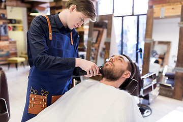 Image showing man and barber with trimmer cutting beard at salon