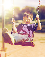 Image showing happy little boy swinging on swing at playground