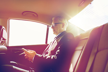 Image showing senior businessman texting on smartphone in car