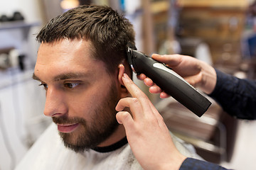 Image showing man and barber hands with trimmer cutting hair