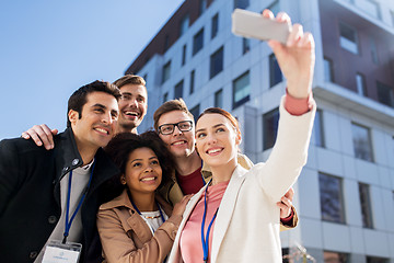 Image showing happy people with conference badges taking selfie