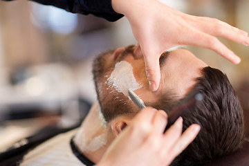 Image showing man and barber with straight razor shaving beard