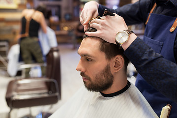 Image showing man and barber cutting hair at barbershop