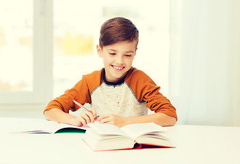 Image showing smiling student boy writing to notebook at home