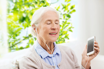 Image showing senior woman with smartphone and earphones at home