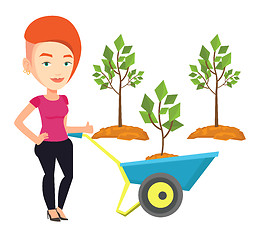 Image showing Woman pushing wheelbarrow with plant.