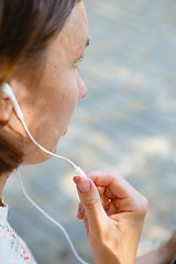 Image showing Young woman talking phone in headphones