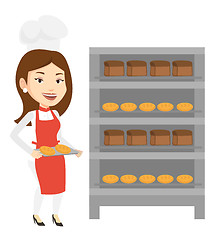 Image showing Happy young female baker holding tray of bread.