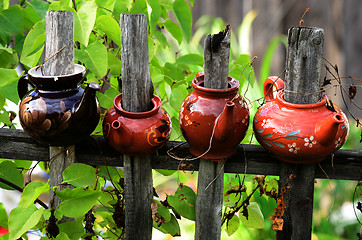 Image showing four ceramic teapots on a wooden fence