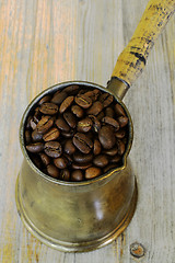 Image showing arabic coffee pot on wooden background with beans
