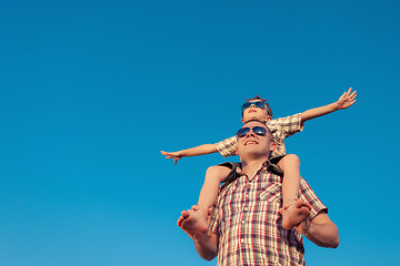 Image showing Dad and son in sunglasses playing near a house at the day time.