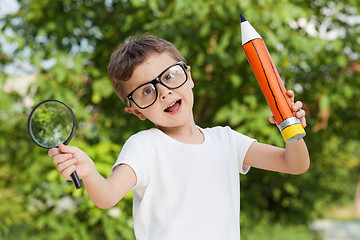 Image showing Smiling young child in a uniform standing against a tree in the 