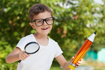 Image showing Smiling young child in a uniform standing against a tree in the 