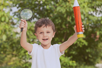 Image showing Smiling young child in a uniform standing against a tree in the 