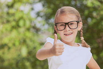 Image showing Smiling young child in a uniform standing against a tree in the 