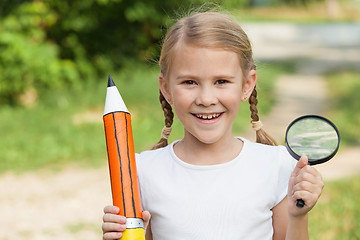 Image showing Smiling young child in a uniform standing against a tree in the 