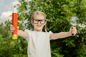 Image showing Smiling young child in a uniform standing against a tree in the 