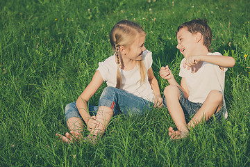 Image showing Two happy children playing near the tree on the grass at the day