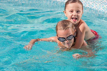 Image showing Two happy children playing on the swimming pool at the day time.