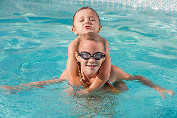 Image showing Two happy children playing on the swimming pool at the day time.