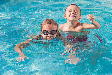 Image showing Two happy children playing on the swimming pool at the day time.